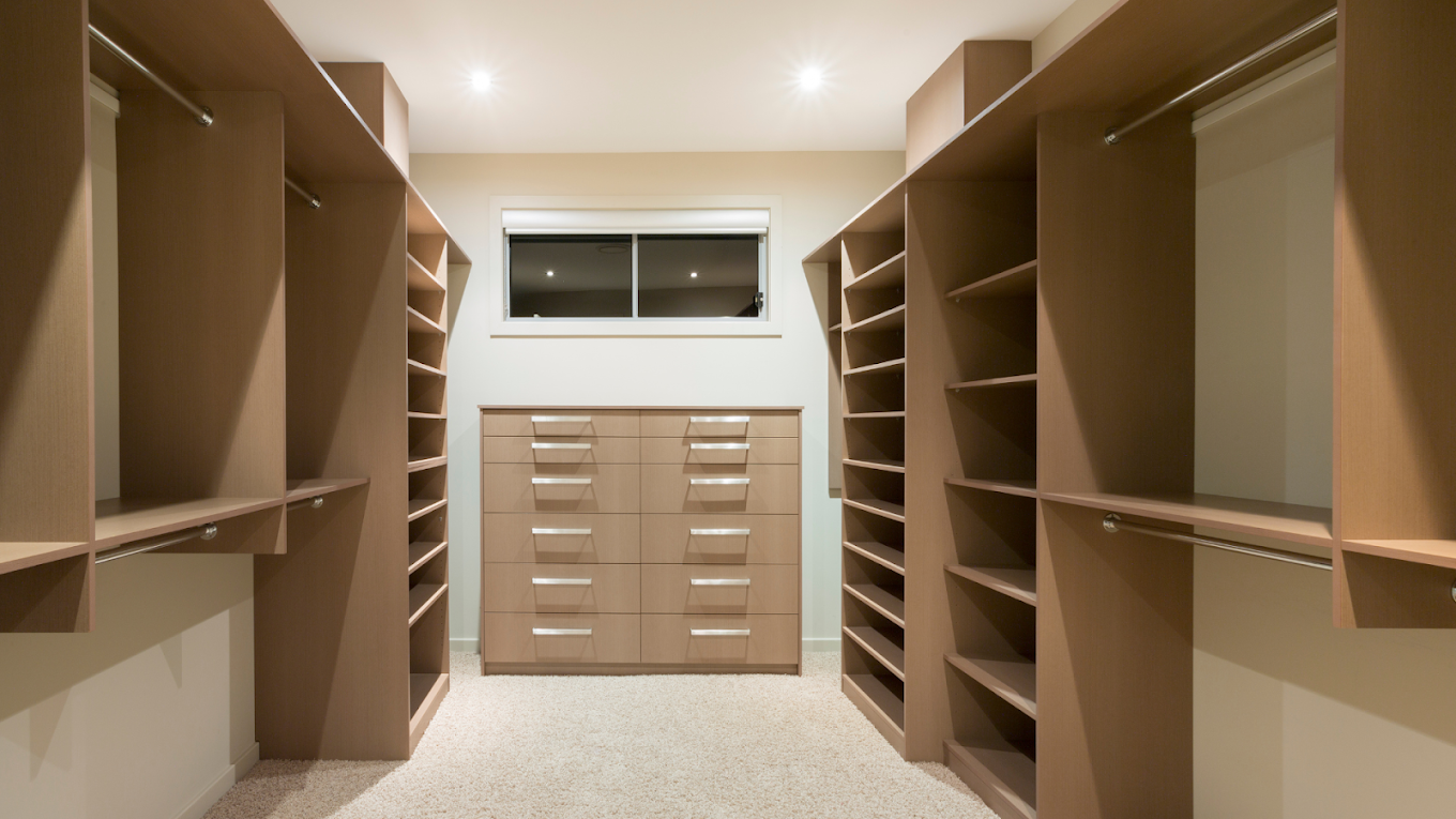 Walk-in closet with custom shelving and central drawer unit.