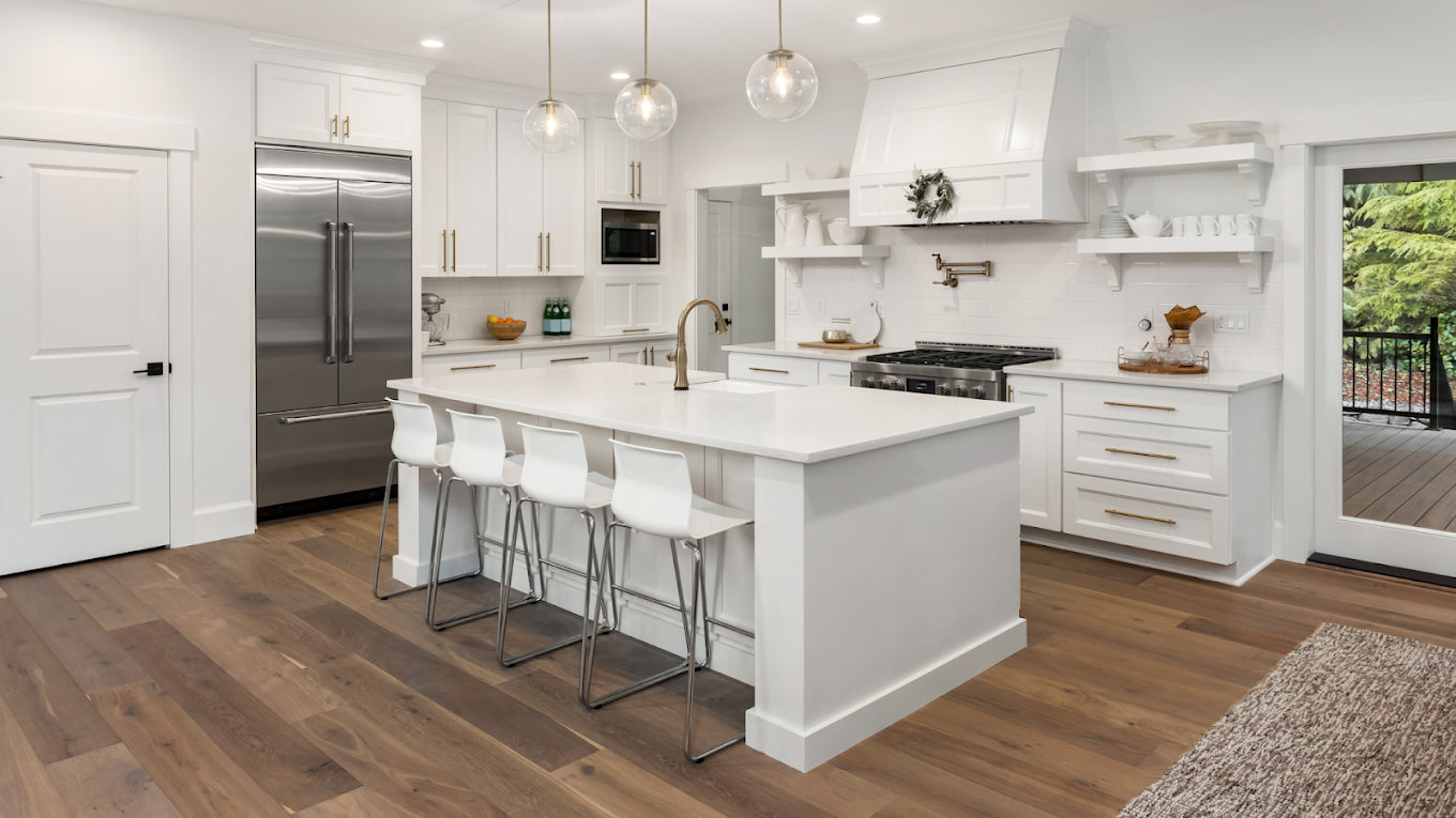 Finished white kitchen with marble island and pendant lighting.