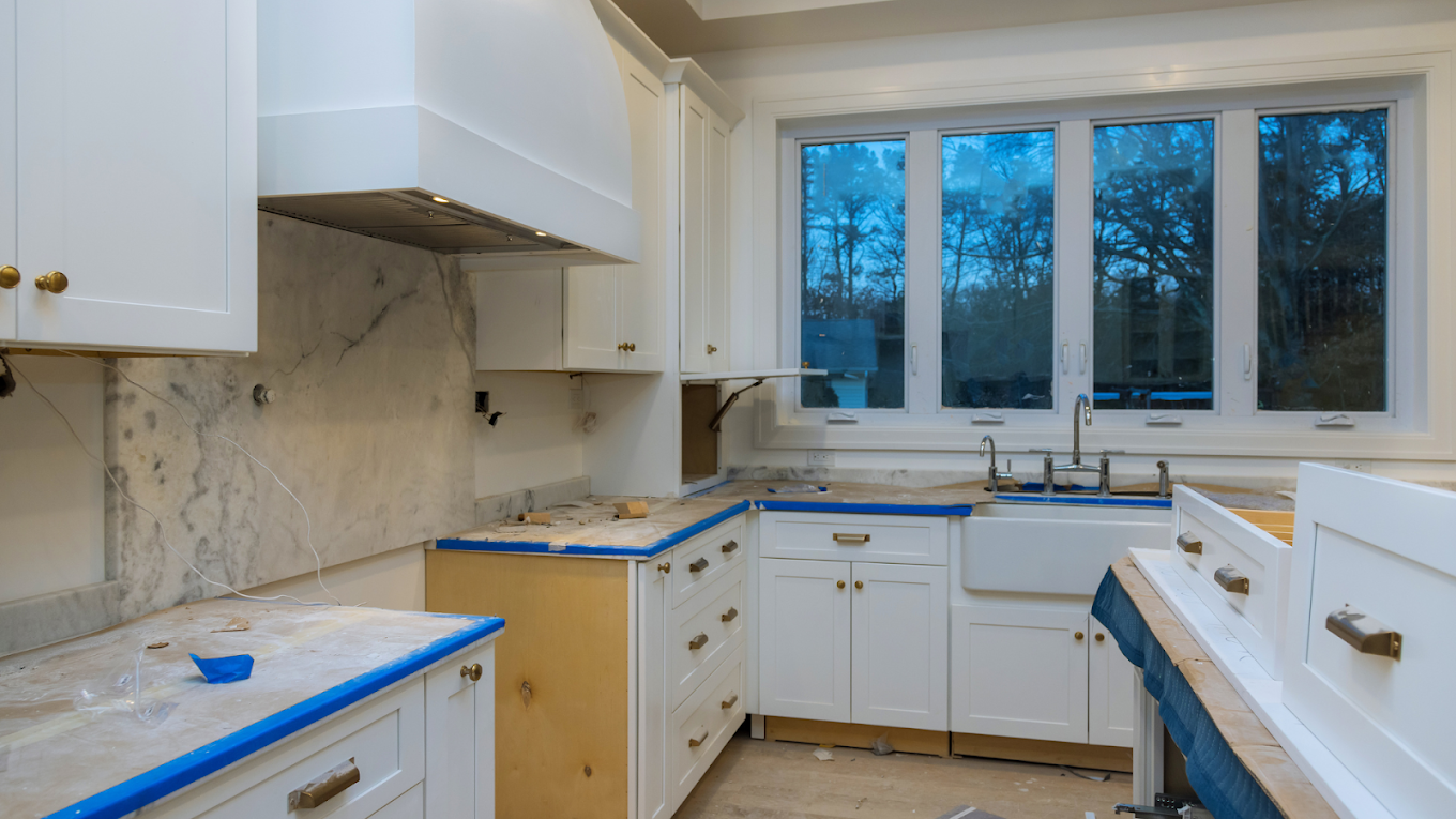 Kitchen mid-renovation with marble countertops and protective tape.