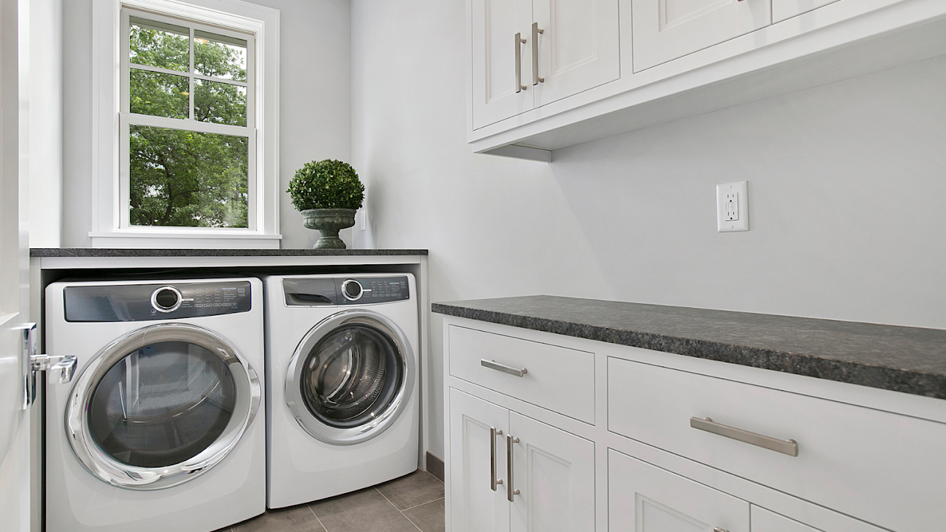 Finished white laundry room with new washer and dryer and built-in cabinetry.
