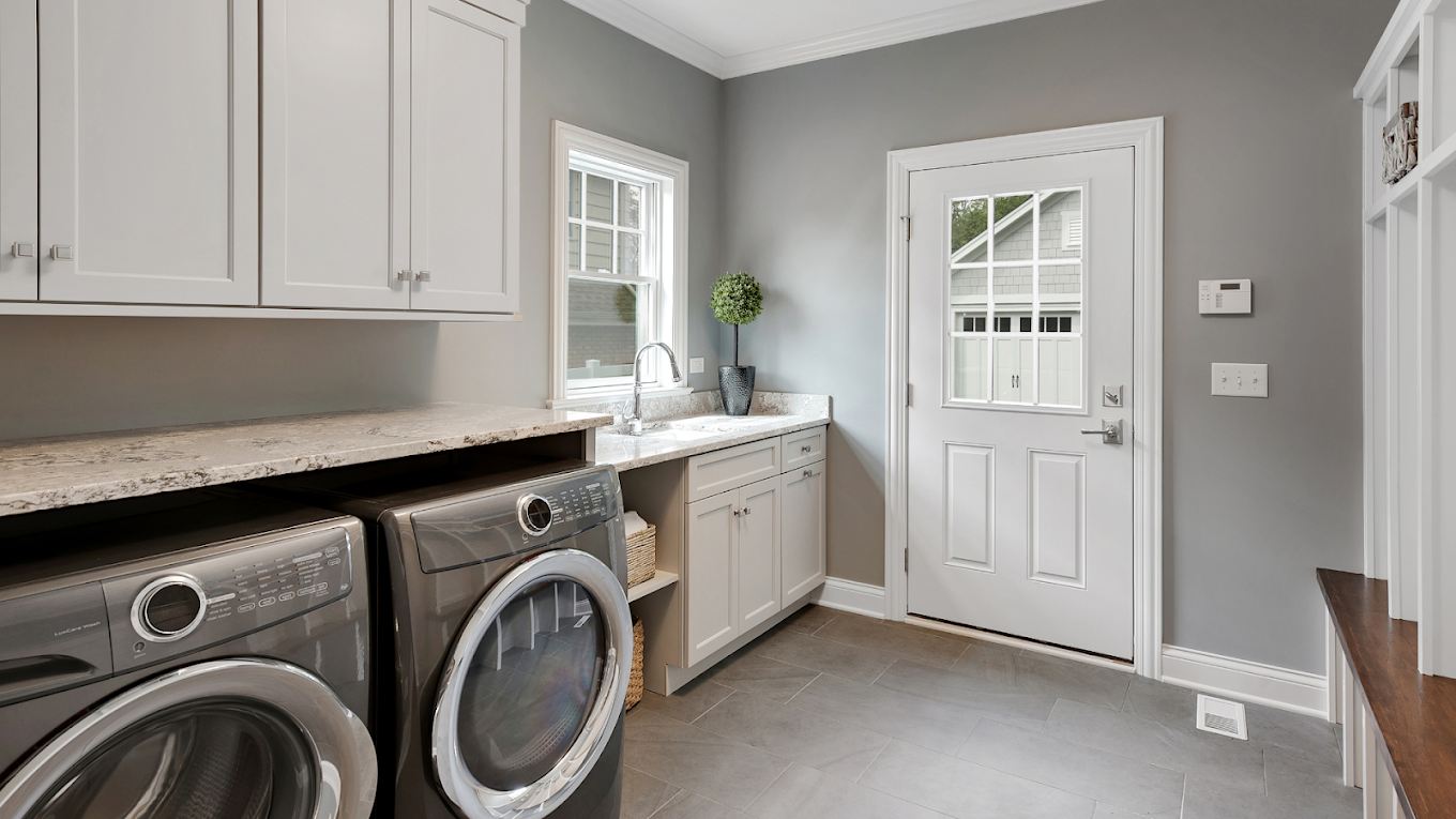 Finished grey laundry room with finished countertop and side door.